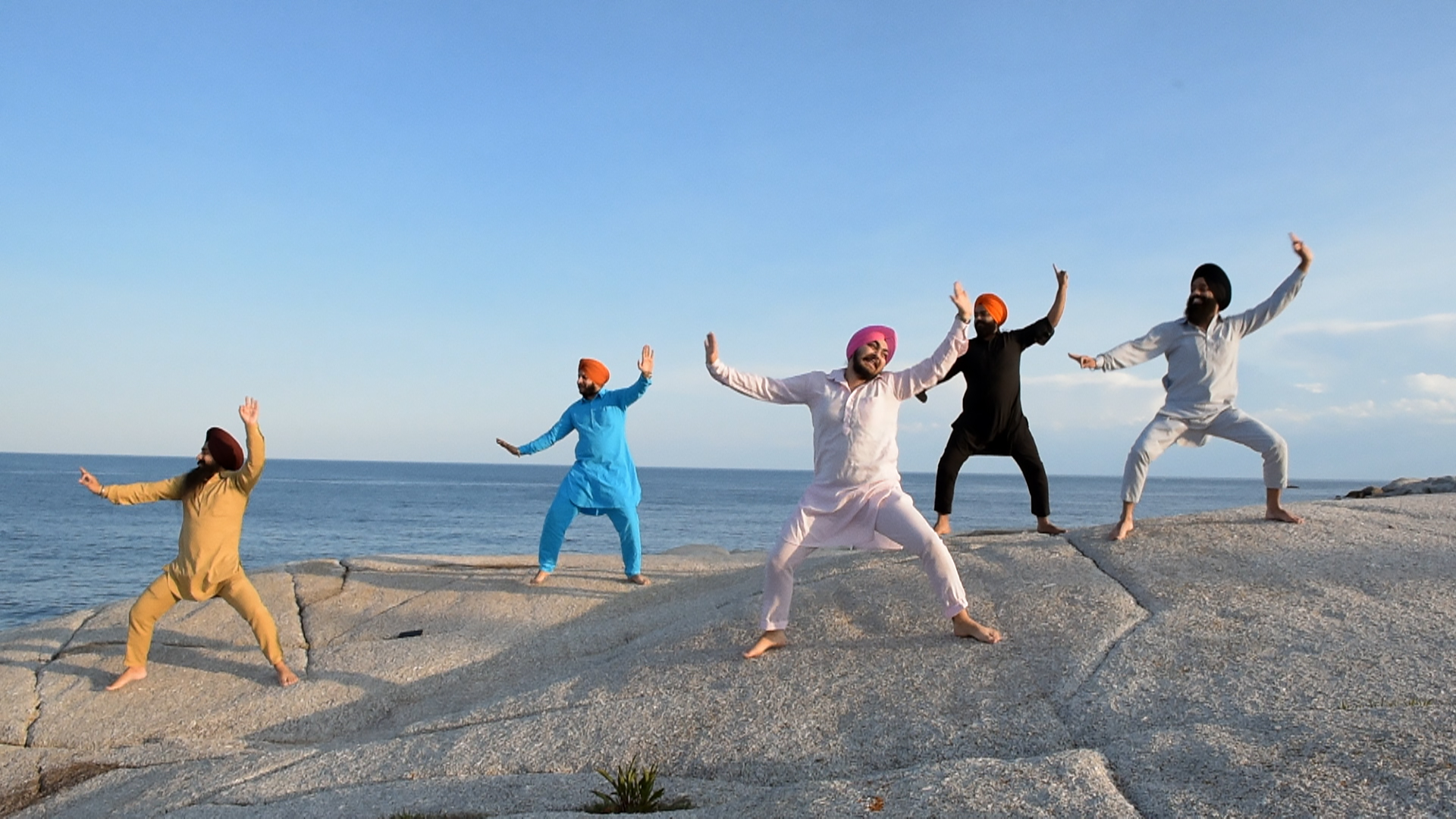 The 5 Bhangra Boys dancing on a ledge with the sea behind them