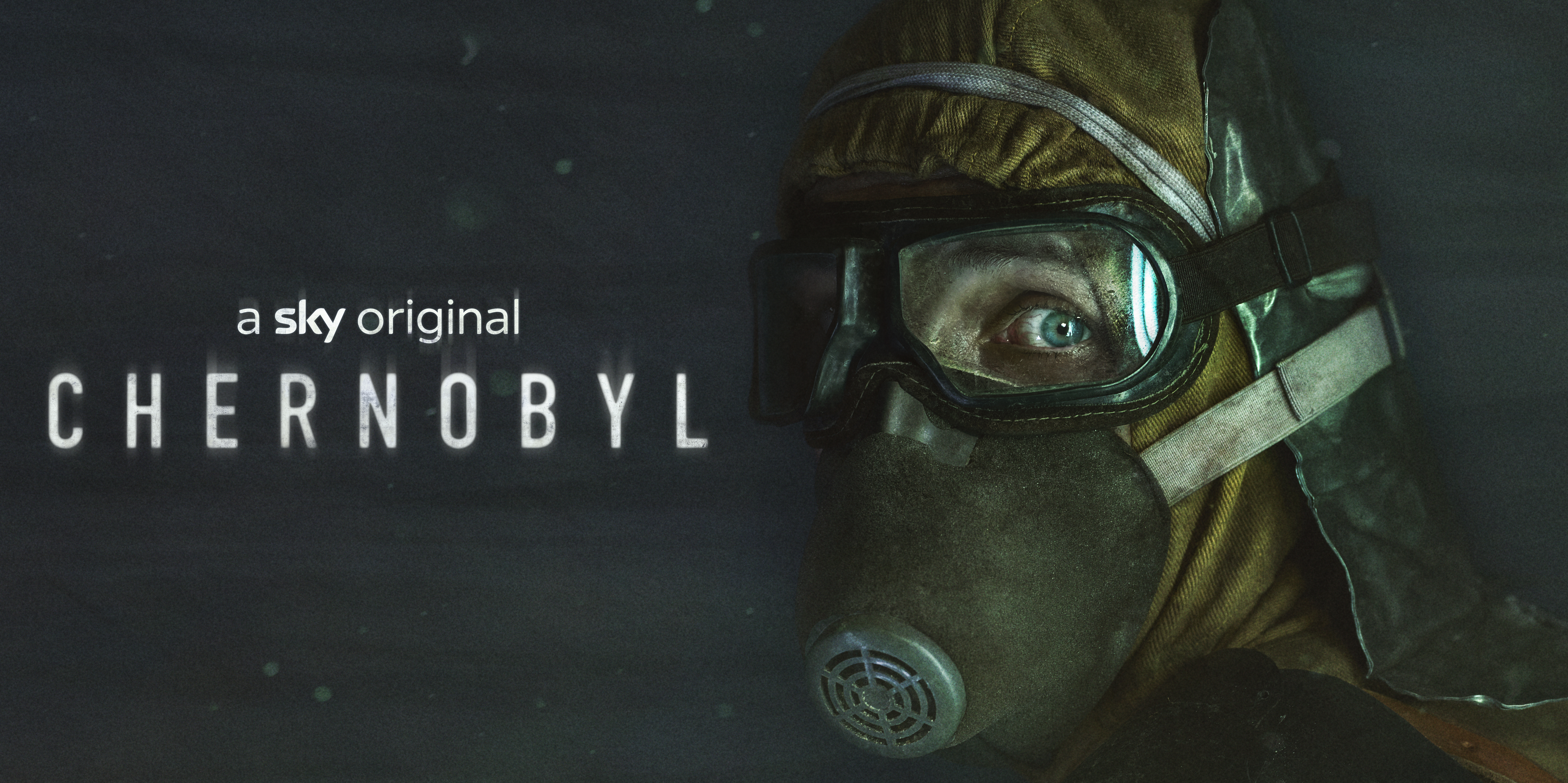 Image courtesy of Sky UK. Poster for Chernobyl. The background is dark and on the left is text which reads "A sky original, CHERNOBYL". On the right is a face with blue eyes staring at us wearing a gas mask, goggles, orange boilersuit hoodie.