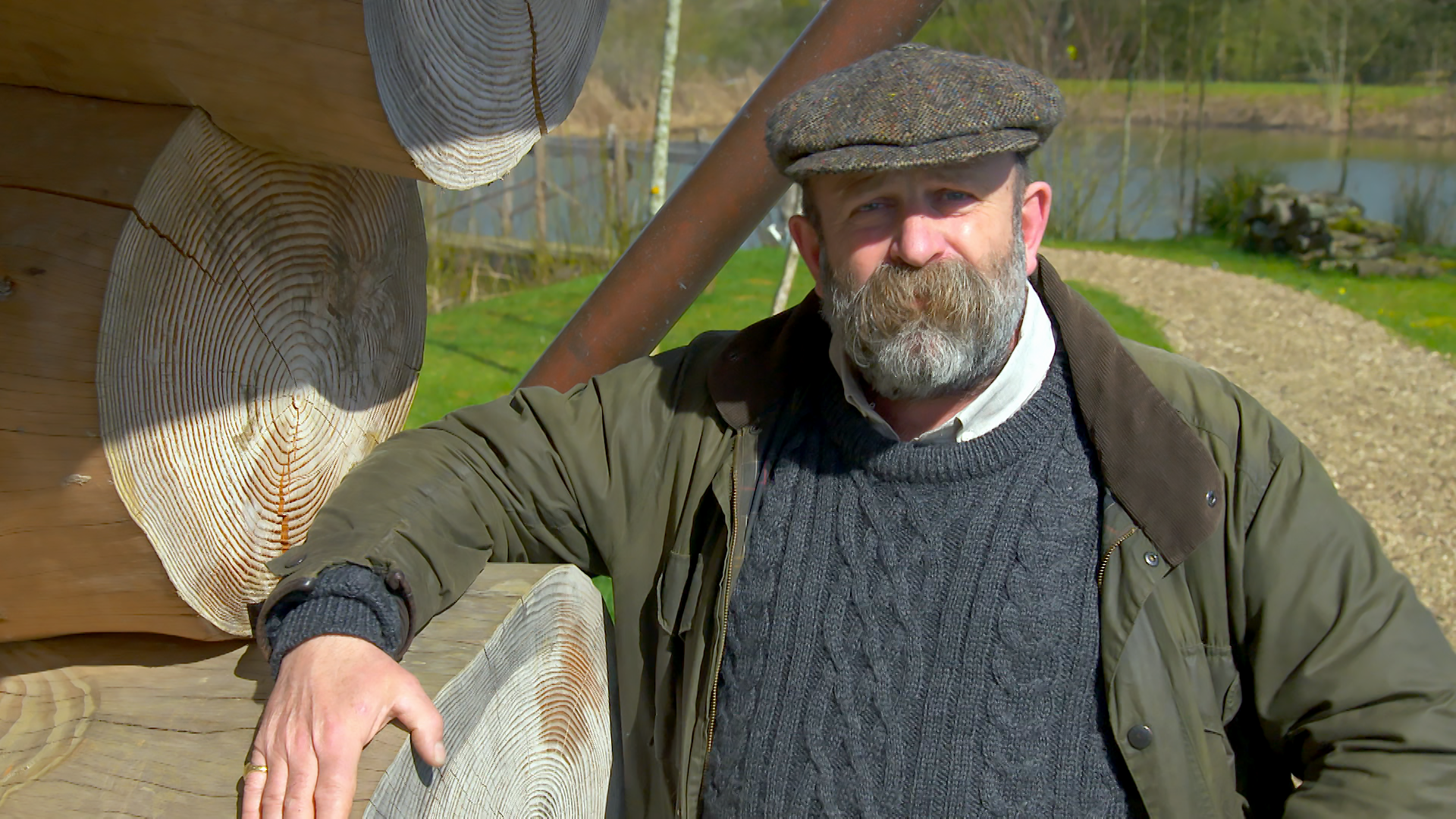 Dick Strawbridge leans against a wood cabin