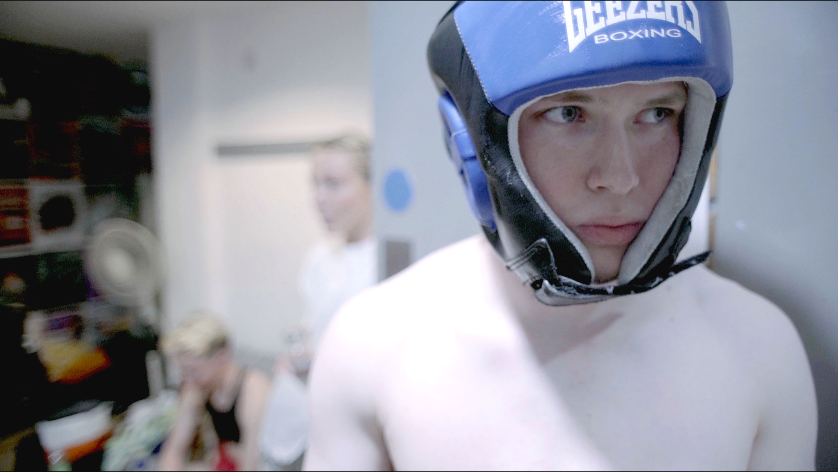 Jill from Come Out Fighting wearing a blue head guard looking determined walking in a office room.